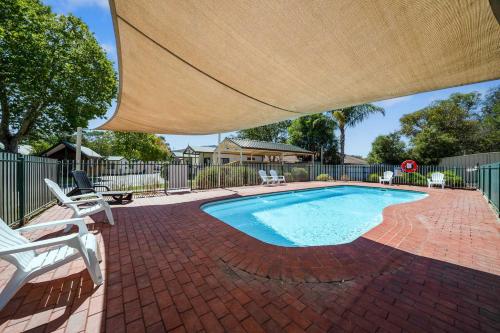 a swimming pool with a large umbrella over it at Albury Holiday Park in Albury