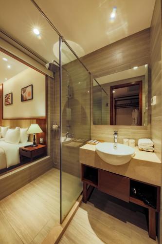 a bathroom with a sink and a bedroom at Green Beach Hotel Nha Trang in Nha Trang