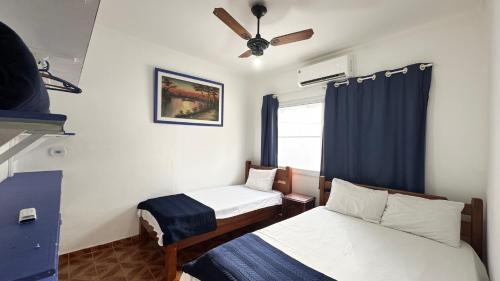 a room with two beds and a ceiling fan at Casa terrea perfeita para familias 100 m da praia do Arpoador, com piscina, churrasqueira, ar condicionado e 4 quartos in Peruíbe