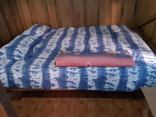 a bed with a blue and white comforter on it at Centro Etnoturístico El Descanso in Térraba