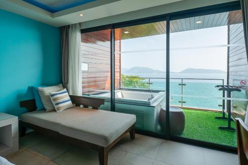 a bedroom with a tub and a large window at Zenmaya Oceanfront Phuket, Trademark Collection by Wyndham in Patong Beach