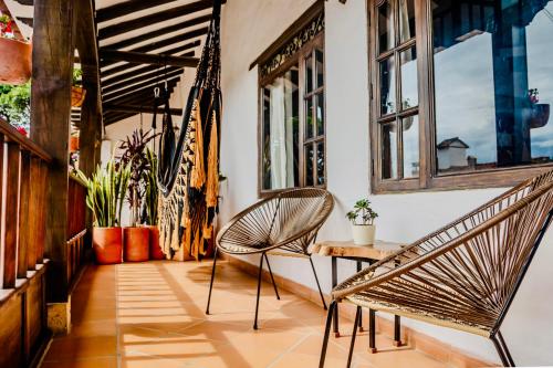 a porch with two chairs and a table and windows at Pancha Mama Hotel Boutique in Villa de Leyva