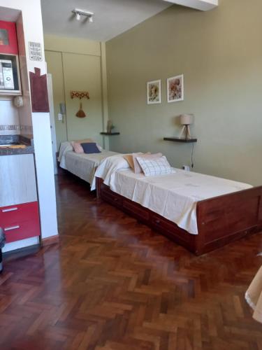 two beds in a bedroom with a wooden floor at Departamento Monoambiente Centro Villa Carlos Paz in Villa Carlos Paz