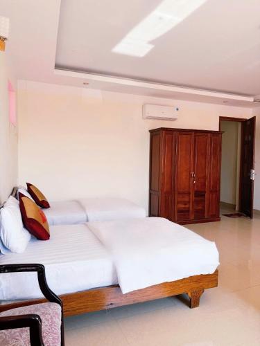 a bedroom with two white beds and a wooden cabinet at An Thái Hotel in Kon Tum