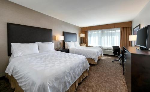 a hotel room with two beds and a flat screen tv at Pacific Stay Hotel in West Covina