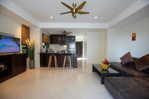 a living room with a couch and a ceiling fan at Baan Chom View Kamala - SHA Plus in Kamala Beach