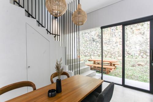 a dining room with a wooden table and some windows at The Banyu House 3 in Bandung