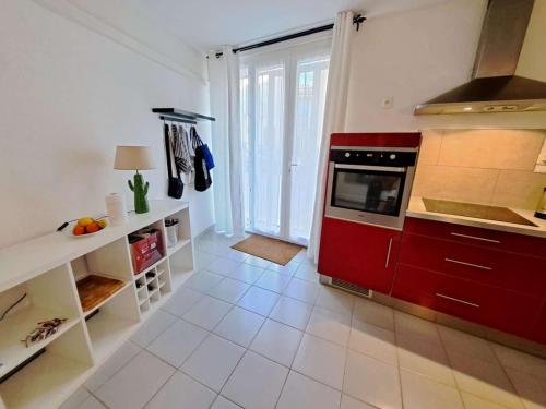 Il comprend une cuisine avec des placards rouges et du carrelage blanc. dans l'établissement Maison de village à Marseillan avec ascenseur et terrasse tropézienne - FR-1-326-850, à Marseillan