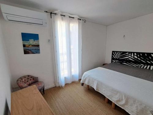 une chambre avec un lit, une chaise et une fenêtre dans l'établissement Maison de village à Marseillan avec ascenseur et terrasse tropézienne - FR-1-326-850, à Marseillan