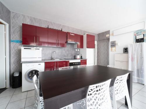 une cuisine avec une table noire et des armoires rouges dans l'établissement Appartement 6 pers au cœur de Mimizan Plage - FR-1-50-168, à Mimizan