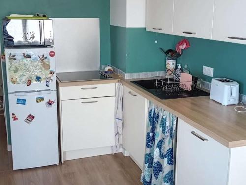 une cuisine avec des armoires blanches et un réfrigérateur blanc dans l'établissement Charmant T2 avec Terrasse à Stella Plage, Animaux Acceptés - FR-1-236-165, à Cucq