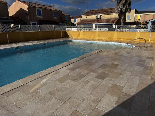 une piscine avec de l'eau bleue dans une cour dans l'établissement Maison Gruissan 3 Pièces, Terrasse et Parking - FR-1-229-894, à Gruissan