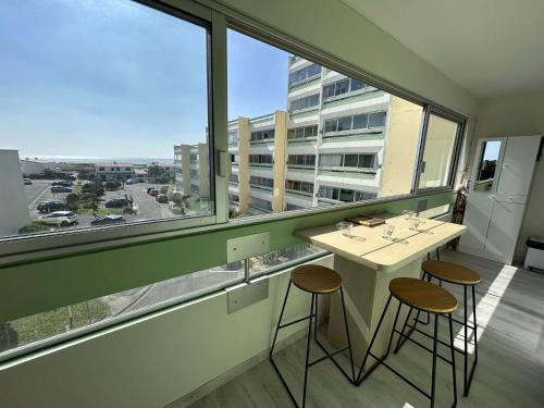 - une table et deux tabourets dans une pièce avec une grande fenêtre dans l'établissement Appartement lumineux 2 pièces, proche plage, parking inclus - FR-1-224C-339, à Saint-Hilaire-de-Riez