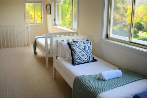 a small bedroom with two beds and two windows at Floriel - By Berry Getaways in Berry