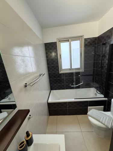 a bathroom with a tub and a toilet and a sink at Kissonerga Sea Breeze Apartments Panoramic Ocean View in Kissonerga