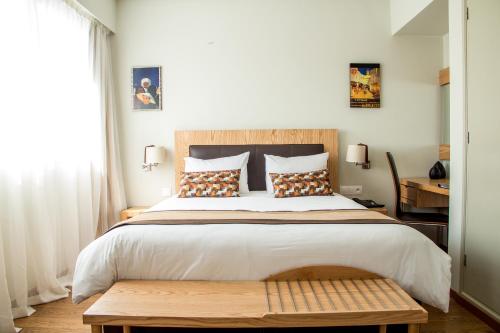 a bedroom with a large bed with a wooden headboard at Le Pietri Urban Hotel in Rabat