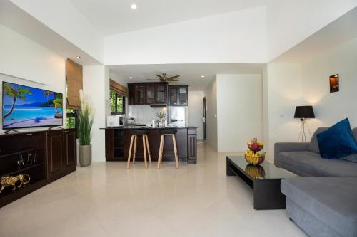 a living room with a couch and a kitchen at Baan Chom View Kamala - SHA Plus in Kamala Beach