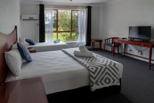 a hotel room with a large bed and a desk at Golf Place Inn Wollongong in Wollongong