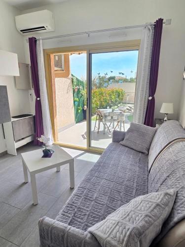 - un salon avec un lit et une vue sur une terrasse dans l'établissement L'instant soleil au Lavandou Apartment, au Lavandou