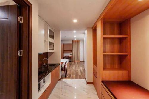 a kitchen with wooden cabinets and a living room at Thúy Apartment Hải Phòng in Hai Phong