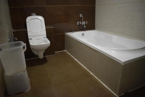 a bathroom with a tub and a toilet and a sink at Hotel Royal Square in Gandhinagar