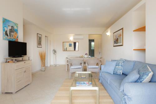 a living room with a blue couch and a table at Blue Coast Suites - Seaside Retreat with Pool in Exclusive Kommeno in Kommeno