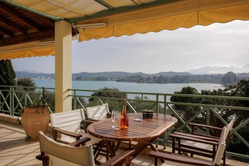 a wooden table and chairs on a patio with a view of the water at Blue Coast Suites - Seaside Retreat with Pool in Exclusive Kommeno in Kommeno