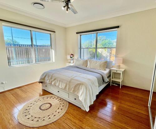 a bedroom with a bed and two windows at Banyan, 14 Montevideo Parade - Spacious pet friendly property with air con and WiFi in Nelson Bay