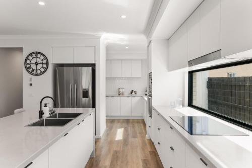 Una cocina con gabinetes blancos y un reloj en la pared. en Our Island Home, en Cowes