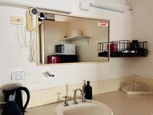 a bathroom sink with a mirror above a sink at Jetty Motel The Entrance in The Entrance