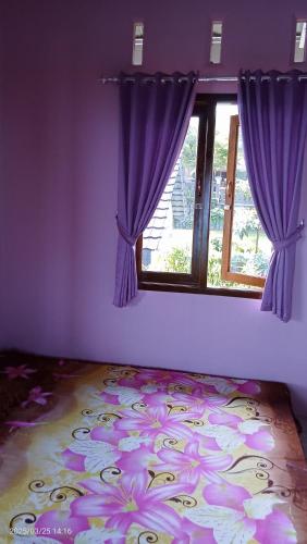 een paarse kamer met een raam met paarse gordijnen bij Uoemah gunung baturaden in Baturaden