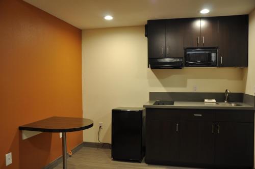 a kitchen with black cabinets and a small table at Motel 6 Maple/Main in Hesperia