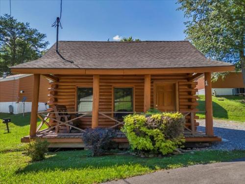 a log cabin with a porch and some bushes at Deluxe 1 BR Cabin with Parking in Pigeon Forge
