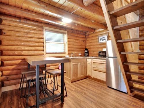 a kitchen with a table and a refrigerator in a log cabin at Deluxe 1 BR Cabin with Parking in Pigeon Forge