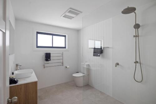 a white bathroom with a shower and a toilet at Gawura in Burrill Lake