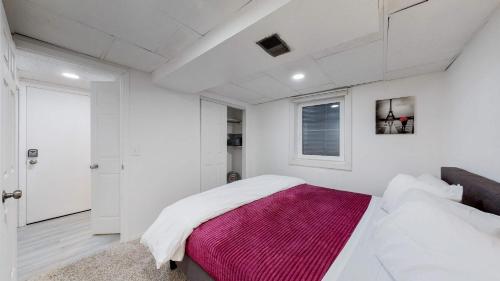 a white bedroom with a bed with a pink blanket at Cozy Mountain-Inspired Lower Unit in Denver in Denver