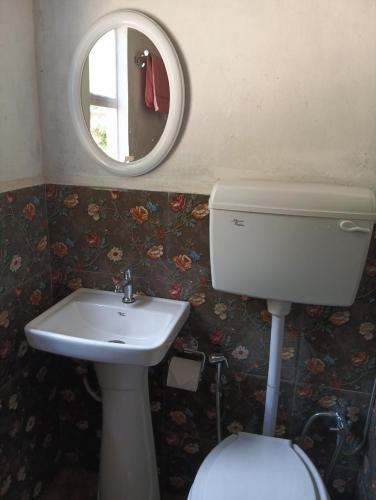 a bathroom with a toilet and a sink and a mirror at Tympang Chalet Home Stay in Dawki