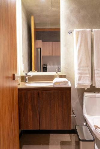 a bathroom with a sink and a toilet and a mirror at TUK Tulum Studios in Tulum