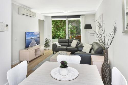 a living room with a table and a couch at Resort Pool and Garden Apartment, Nelson Bay in Nelson Bay