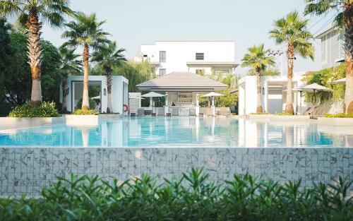 a swimming pool with palm trees and a building at Health Land Resort & Spa in Pattaya South