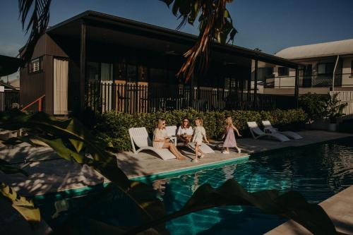 a group of people sitting next to a swimming pool at Park St in Evans Head