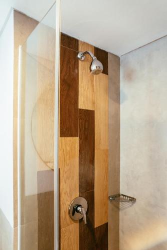 a shower with a glass door with a shower head at Nadi Hotel Legian in Legian