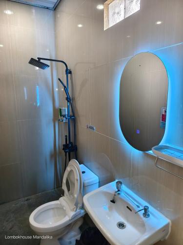 a bathroom with a sink and a toilet and a mirror at Lombokhouse Mandalika in Kuta Lombok