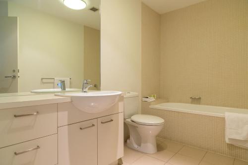 a bathroom with a sink and a toilet and a tub at AKOM AT Docklands in Melbourne