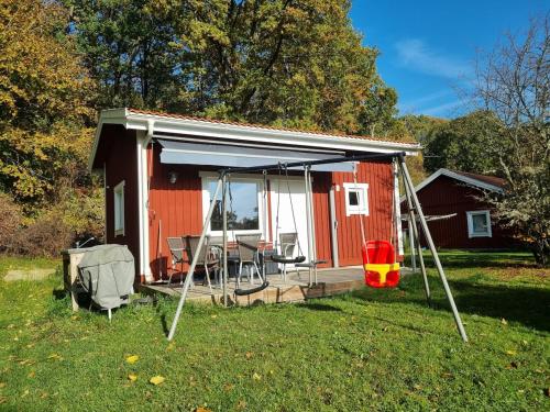 a red shed with a porch and a swing at Sauna&Jacuzzi-New guesthouse, private in nature in Vallda
