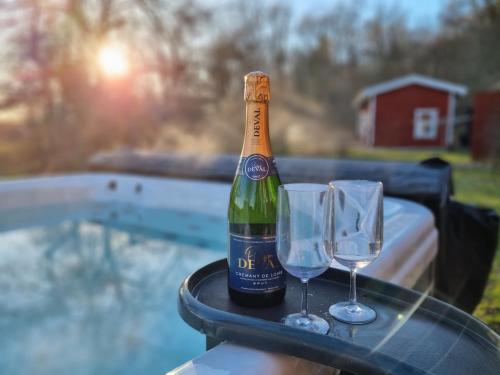 a bottle of champagne and two glasses on a table at Sauna&Jacuzzi-New guesthouse, private in nature in Vallda
