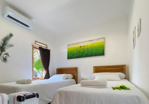 two beds in a room with white walls at Winy Home Lovina in Lovina