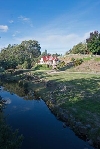 a house on a hill next to a river at CRABTREE RIVERFRONT COTTAGES 2 cottages EMILY & ELIZA COTTAGES Beautiful riverfront peaceful location RELAX & ENJOY in Huonville