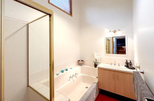 une salle de bain avec une baignoire et un lavabo dans l'établissement Anchorage Cottage Ventnor, Phillip Island - pet friendly, free WiFi, linen included, à Ventnor