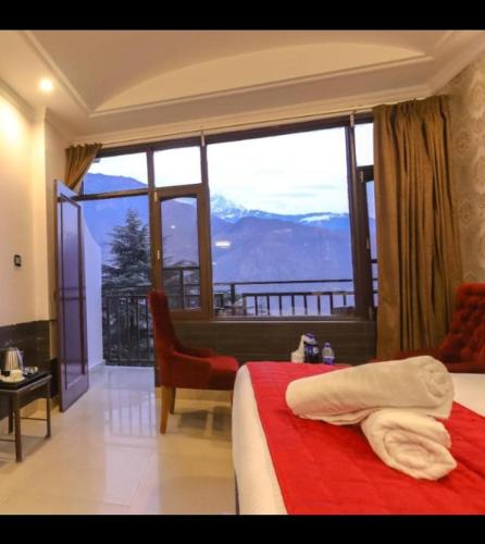 a hotel room with a bed and a large window at Hotel Holiday Hill Mcleodganj-Near to Dalai Lama Temple & Mall Road in Dharmsala